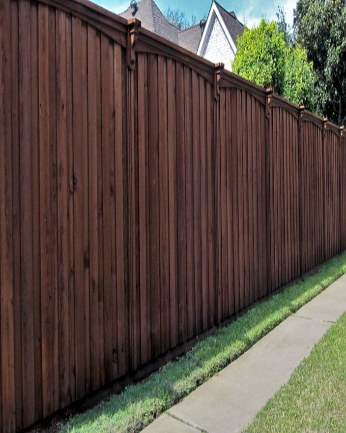 Tall dark-stained privacy fence with arched topcap